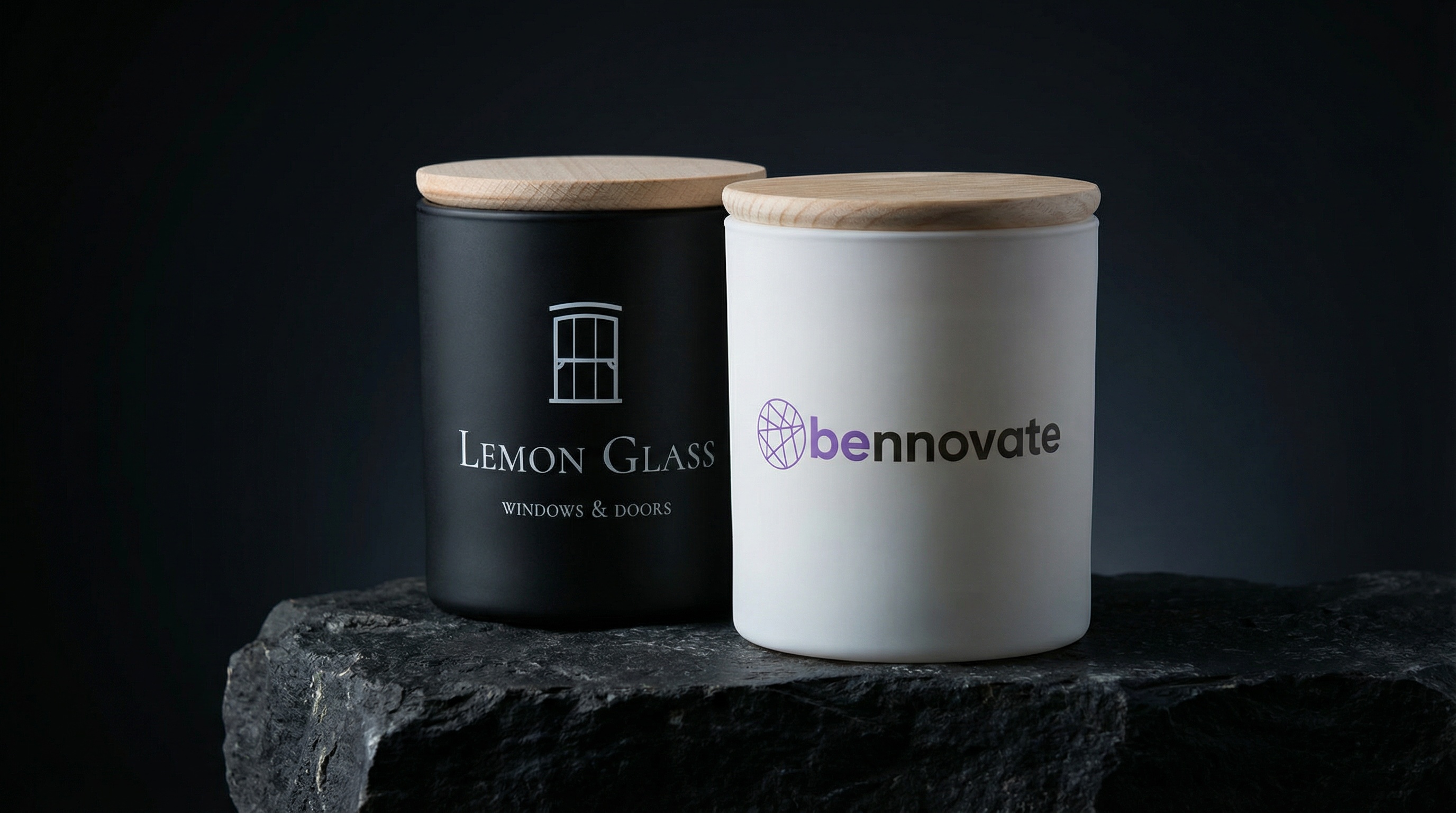 Dwie świece sojowe z logo firmy — czarna Lemon Glass i biała Bennovate z drewnianymi pokrywkami